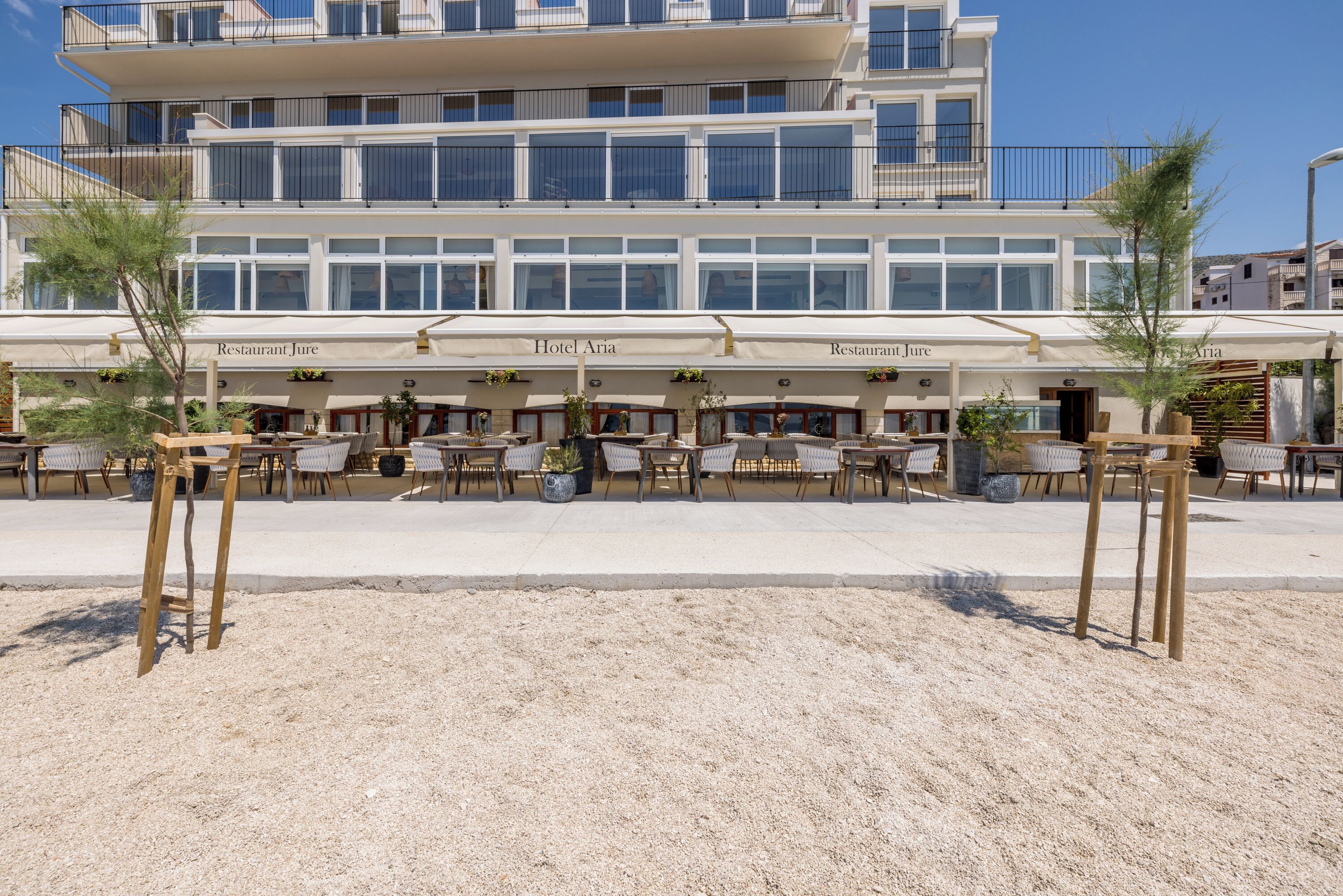 A beachfront hotel with outdoor seating and a clear view of the sea.