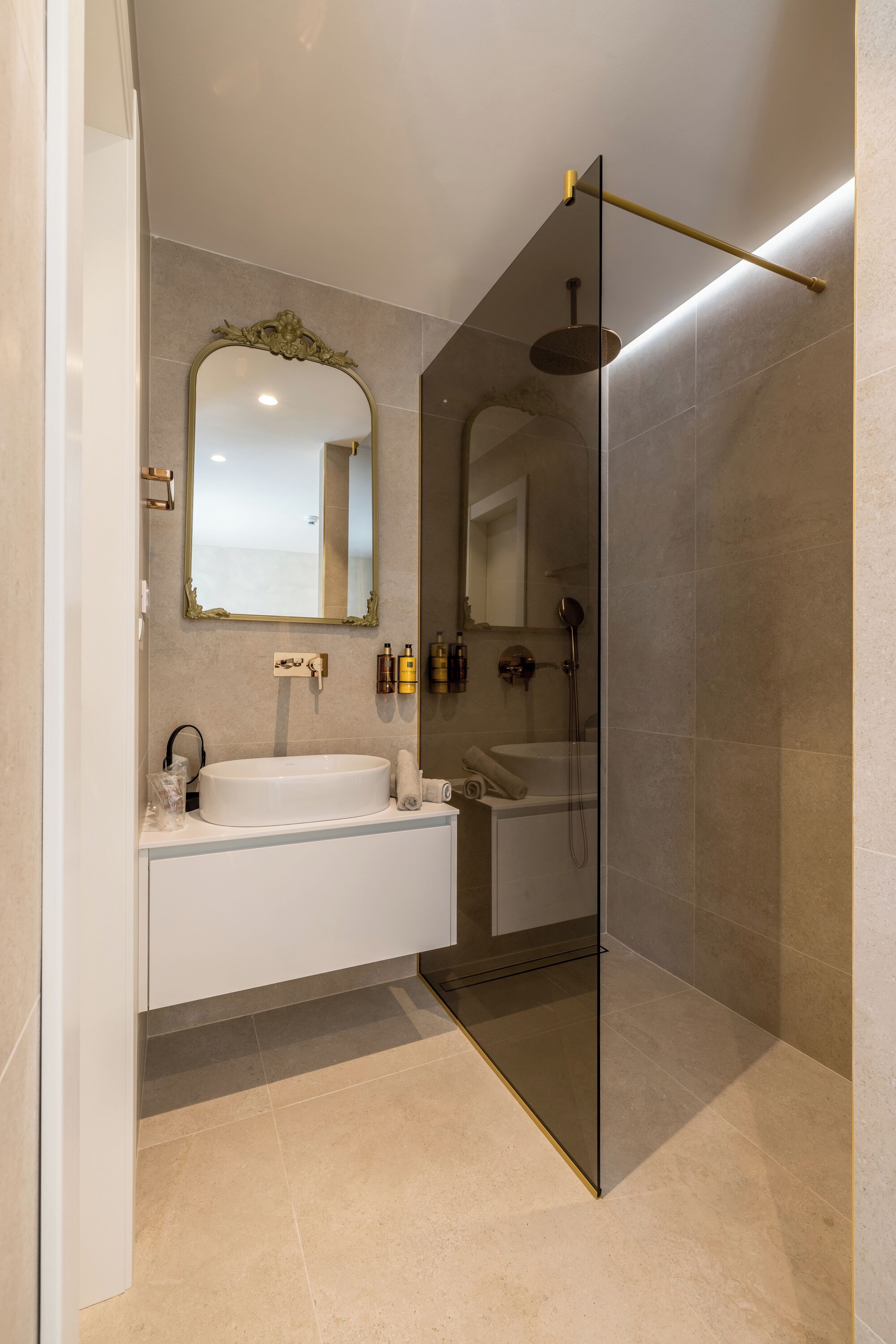 Een moderne badkamer met een douchecabine van glas, een grote spiegel en een wastafelmeubel met wastafel en handdoekhouder.