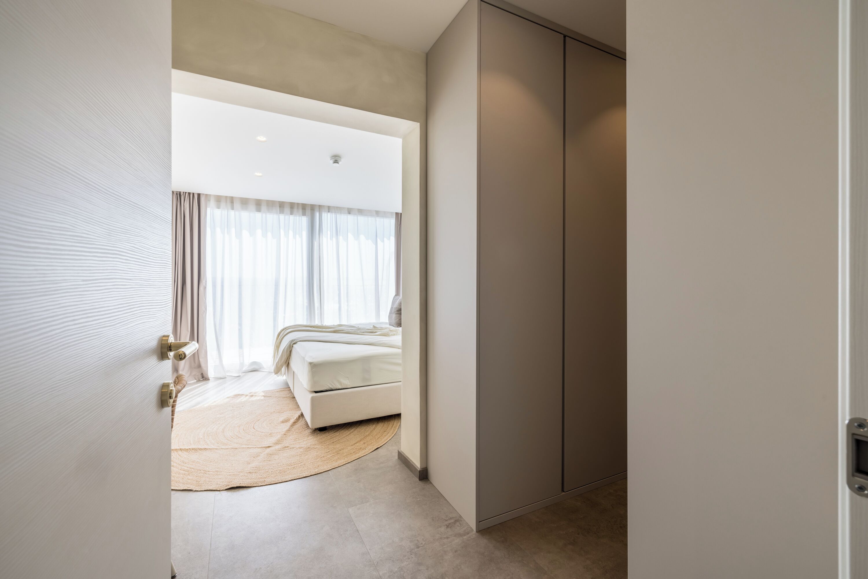 Une chambre à coucher moderne avec un lit, une grande armoire et un tapis rond.