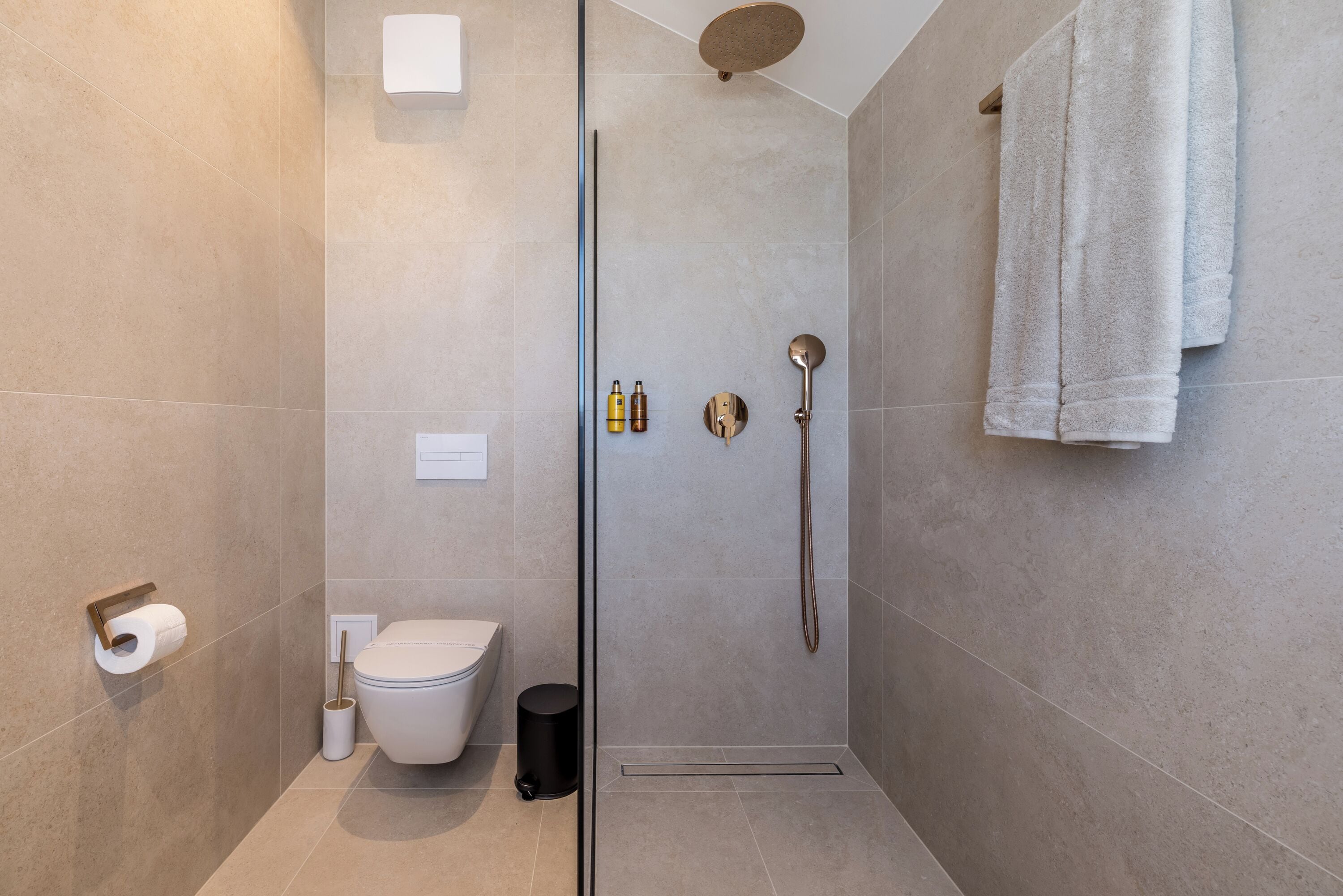 A modern bathroom with a glass-enclosed shower, a toilet, and a towel rack.