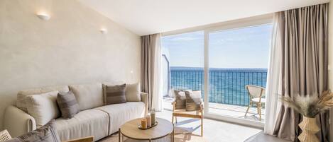 A modern living room with a sofa, a round coffee table, and a view of the sea through large windows.
