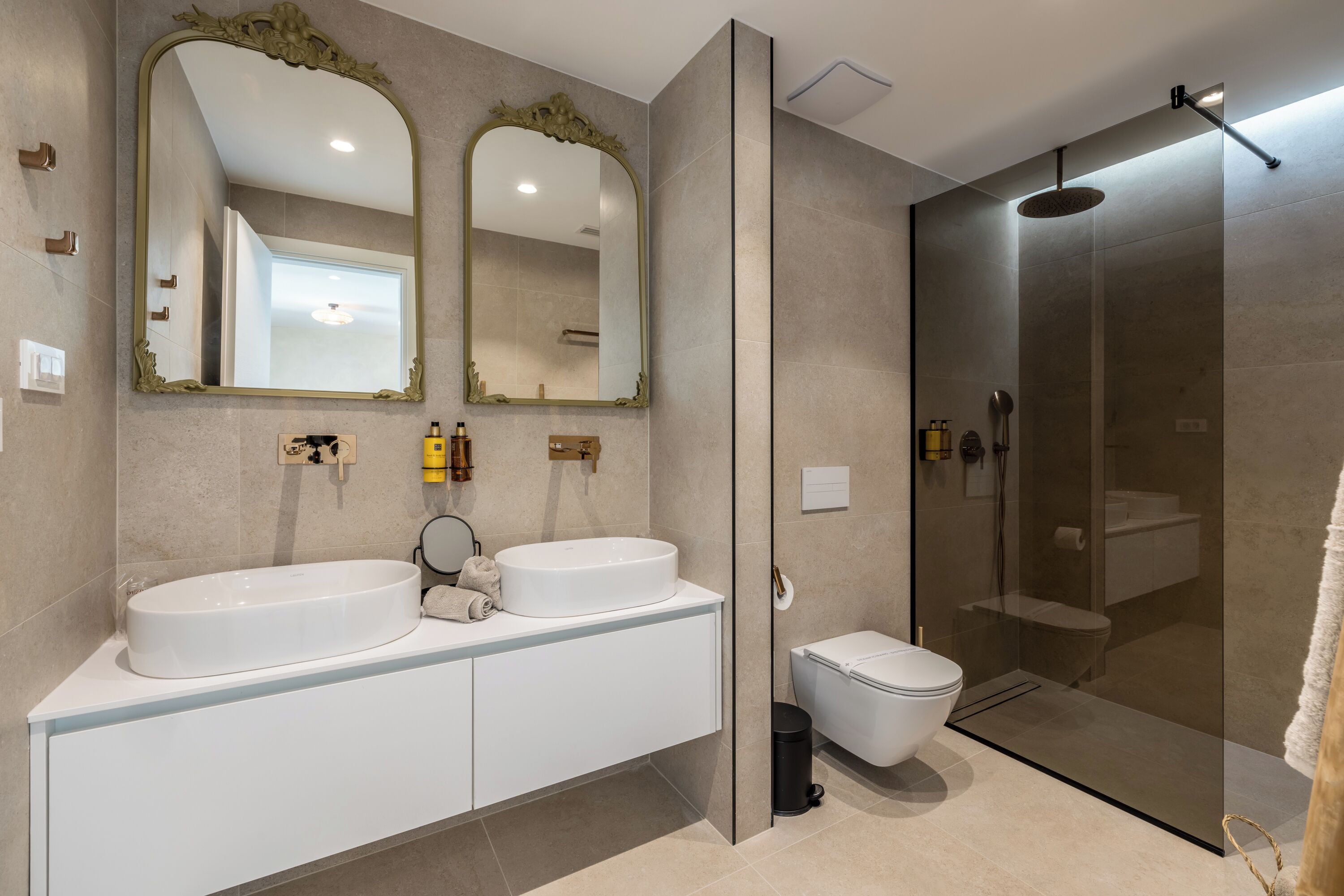 A modern bathroom with two sinks, a toilet, and a glass-enclosed shower.