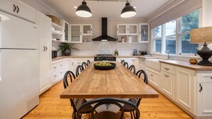 A kitchen with white cabinetry, a wooden dining table, and pendant lighting. - Oliver s Cottage Yarra Valley Spa and Sauna (Yarra Glen)