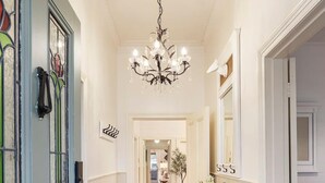 A hallway with wooden flooring, a chandelier, a door with stained glass, and a small table with a plant. - Oliver s Cottage Yarra Valley Spa and Sauna (Yarra Glen)