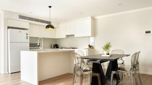 A modern kitchen with a central island, white cabinetry, and a black pendant light. - Balmain Family Tranquility - Harbour Views (Balmain East)