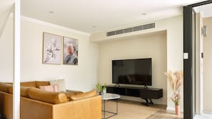 A modern living room with a sofa, a flat-screen TV, and artwork on the wall. - Balmain Family Tranquility - Harbour Views (Balmain East)
