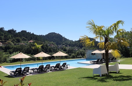 Una piscina techada, una piscina al aire libre, sombrillas