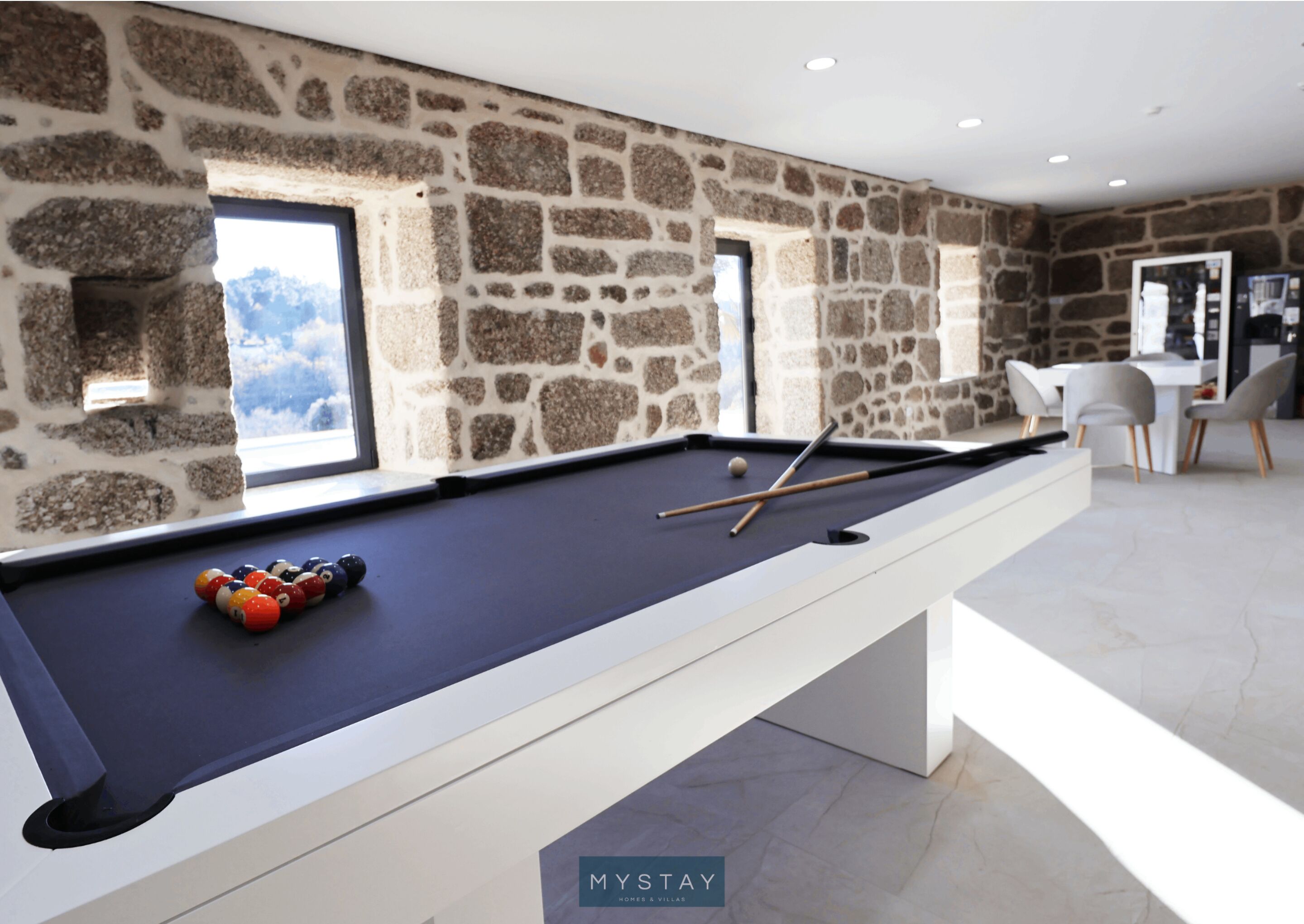 Een pooltafel in een moderne ruimte met stenen muren en uitzicht op het landschap.