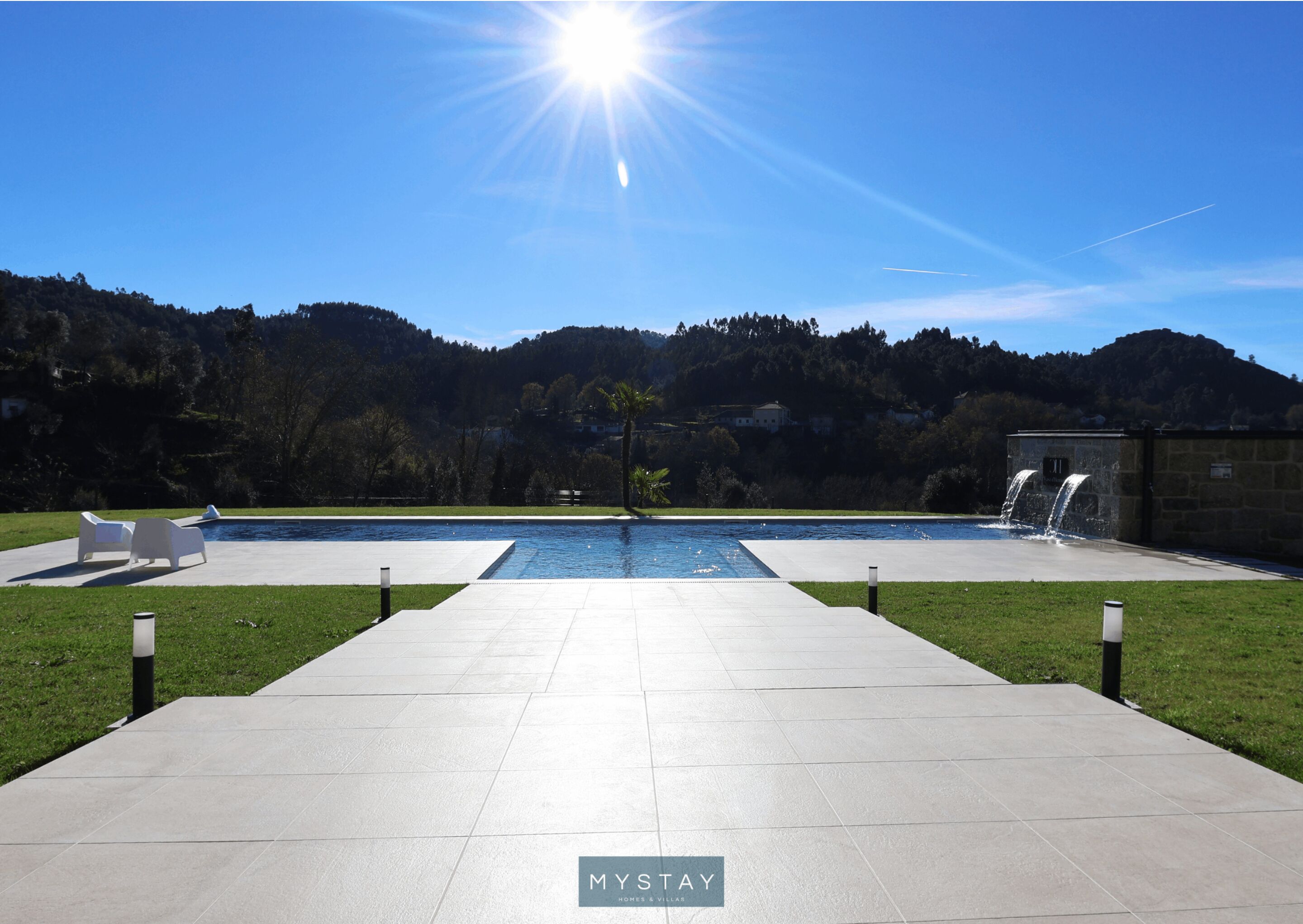 Un espace piscine extérieur moderne offrant une vue dégagée sur les collines environnantes et baigné d’un soleil éclatant.
