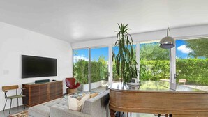 Ein modernes Wohnzimmer mit Flachbildfernseher, einer Couch, einem Couchtisch und einem Flügel.
