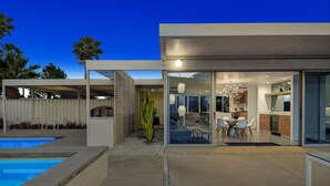 Ein modernes Haus mit Swimmingpool, Terrasse und einem Wintergarten.