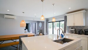 A modern kitchen with a central island, pendant lighting, and a view to the outside. - The Yucca Hotel- Entire Boutique Buyout (Desert Hot Springs)