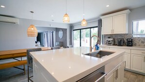 A modern kitchen with a large island, white cabinetry, and pendant lighting. - The Yucca Hotel- Entire Boutique Buyout (Desert Hot Springs)