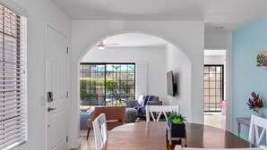 Un comedor con una mesa redonda, sillas blancas y vistas al patio exterior.