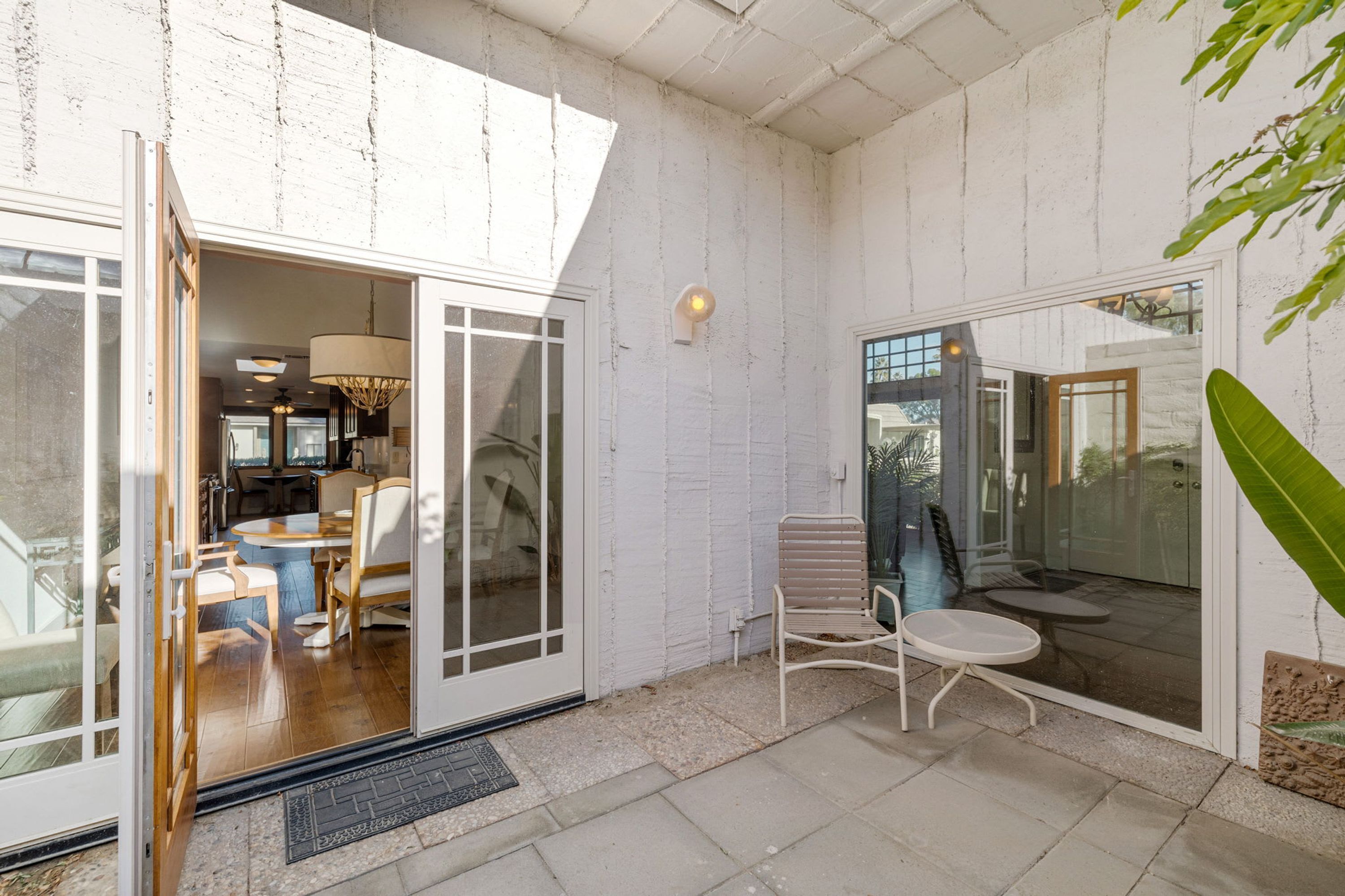 Ein modernes Interieur mit Essbereich, einer Sitzecke mit Tisch und Stühlen sowie einer großen Glasdoor, die nach draußen führt.