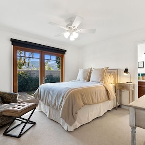 Relax in this serene bedroom with a large bed, ceiling fan, and garden view.