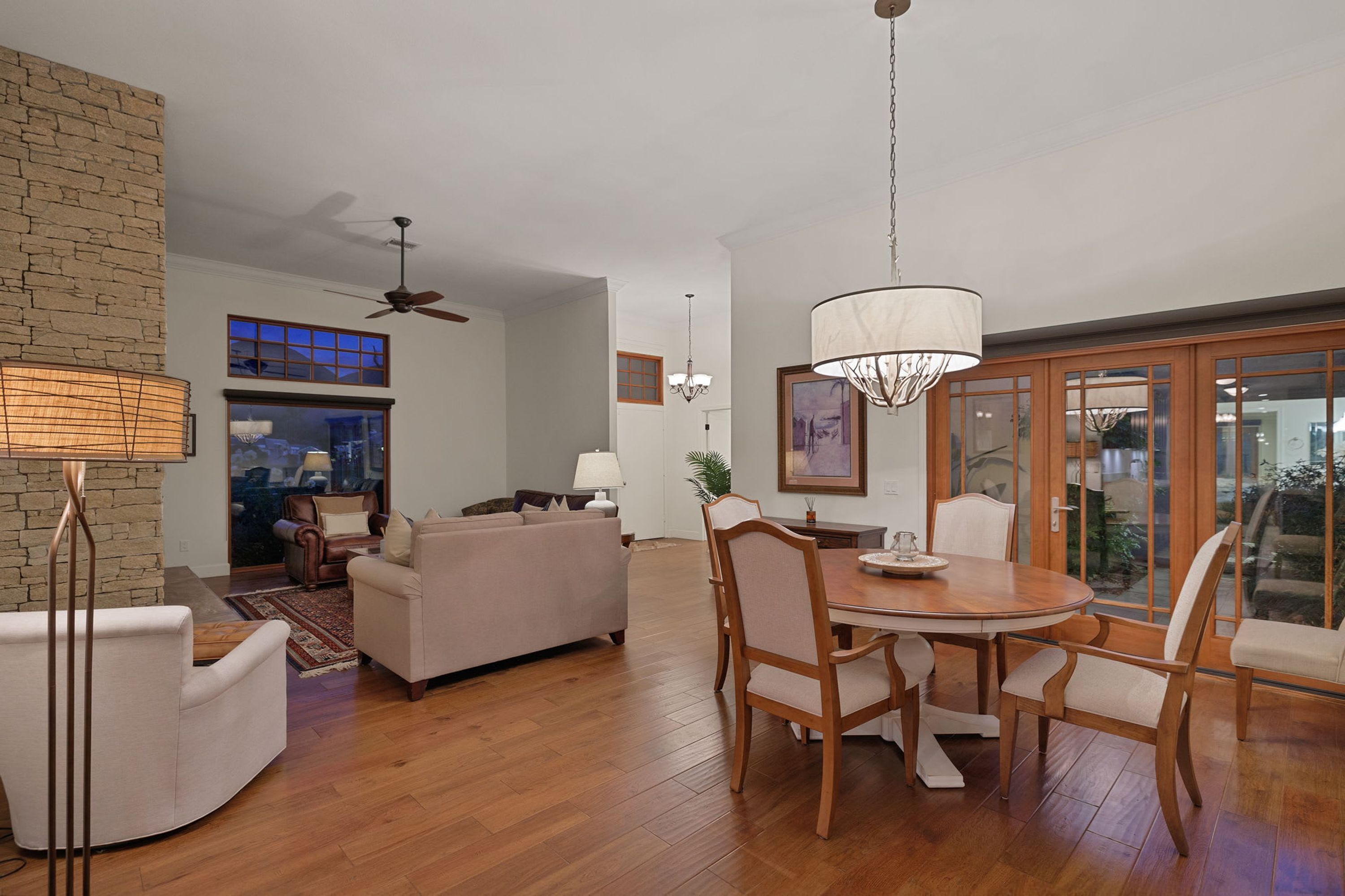 A spacious living room with a dining area, a fireplace, and a view through large glass doors.