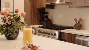 Eine moderne Küche mit Holzschränken, einem Edelstahlherd und einer weißen Arbeitsplatte.