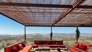 Un espacio de estar al aire libre con sofás rojos y vistas a colinas ondulantes.
