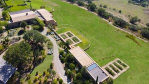 Vista aérea de una propiedad con un gran campo verde, un edificio con panel solar y una piscina.