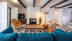 A living room with a white brick fireplace, a television, and modern furniture. - Mountain View Mid-century (Palm Springs)