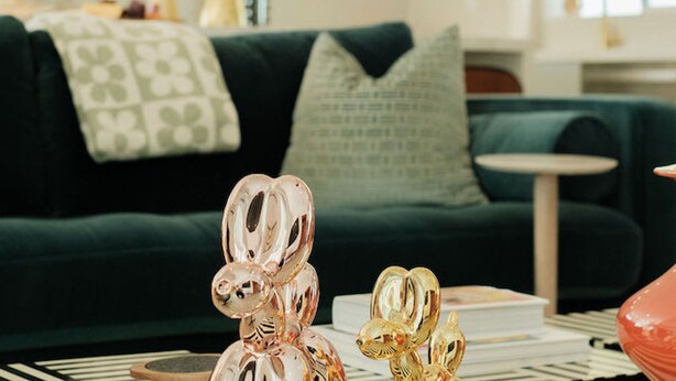A modern living room with a dark green sofa, a small round table, and decorative glass sculptures. - Mod Hotel in Palm Springs (Palm Springs)