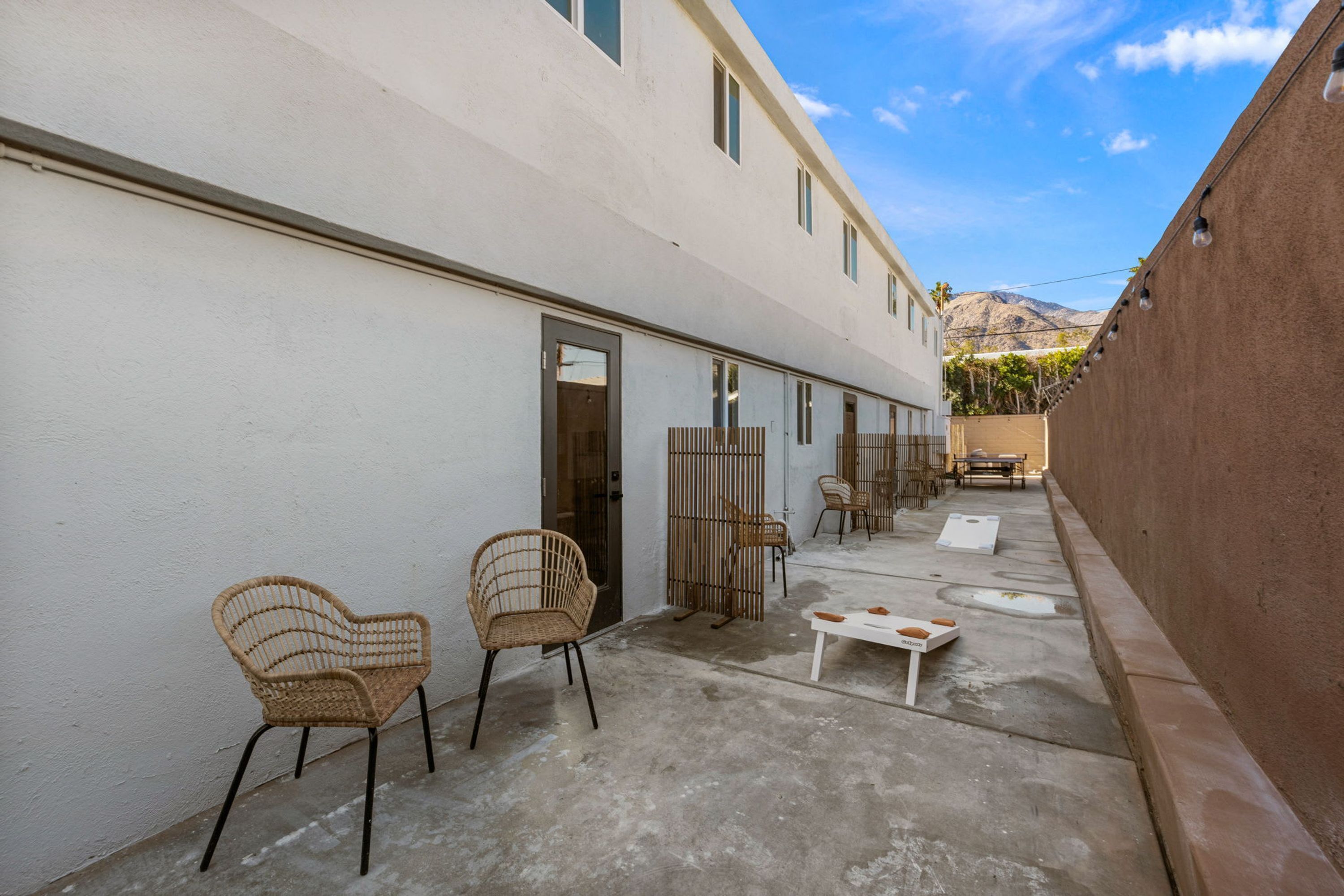 A courtyard with wicker chairs, a small table, and a wooden fence.