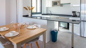 A modern kitchen with white cabinets, a stainless steel refrigerator, and a microwave. - Camporrosso 1C by Bookaparadise (Finestrat)