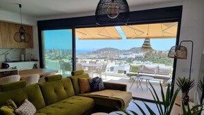 Una sala de estar moderna con un sofá verde, una mesa redonda y un amplio ventanal con vistas a la ciudad.