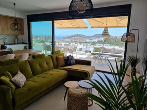 A modern living room with a green sofa, a round table, and a large window offering a city view. - Casa la Vista by Bookaparadise (Finestrat)