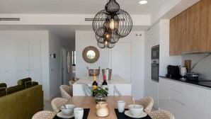 Una cocina moderna con armarios blancos, encimera de madera y una lámpara colgante.
