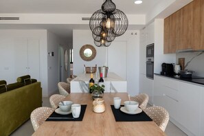 A modern kitchen with white cabinets, a wooden countertop, and a hanging light fixture. - Casa la Vista by Bookaparadise (Finestrat)
