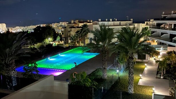A nighttime view of a swimming pool with a cityscape in the background. - Mediterranean Views by Bookaparadise (Finestrat)
