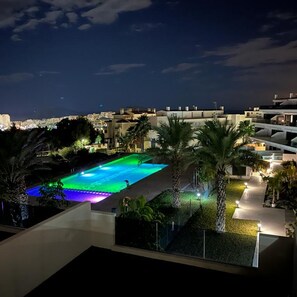 A nighttime view of a swimming pool with a cityscape in the background. - Mediterranean Views by Bookaparadise (Finestrat)
