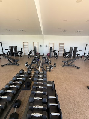 A gym with various exercise equipment, including dumbbells and weight machines, arranged in rows. - Villa Esmeralda 20 by Bookaparadise (Finestrat)