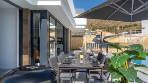 An outdoor dining area with a grill, dining table, chairs, and a large umbrella. - Villa Esmeralda 20 by Bookaparadise (Finestrat)