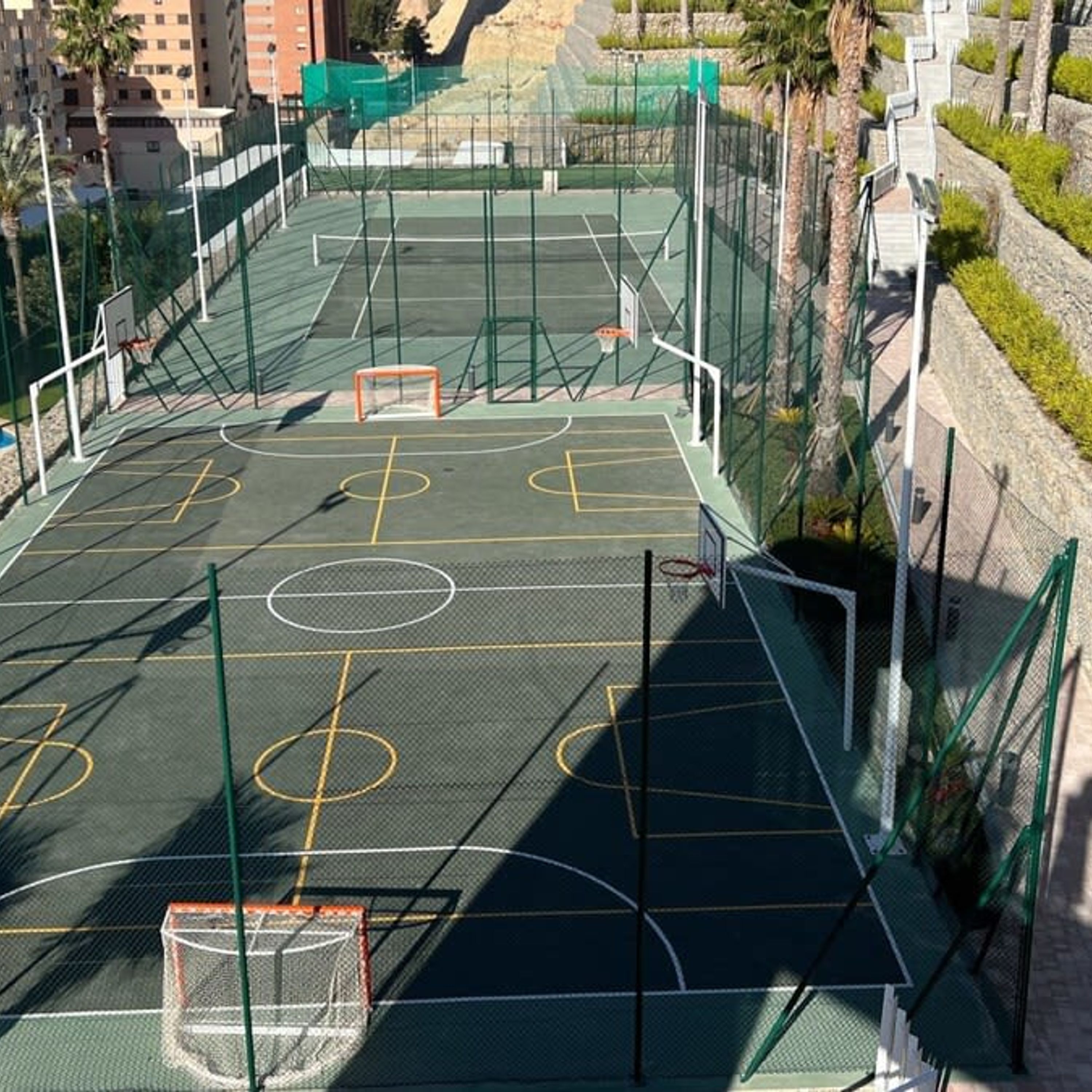 Een buitenbasketbalveld met net, basket en een omheining.