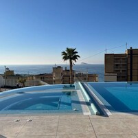 Una piscina en la azotea con vistas despejadas al mar y una montaña a lo lejos.