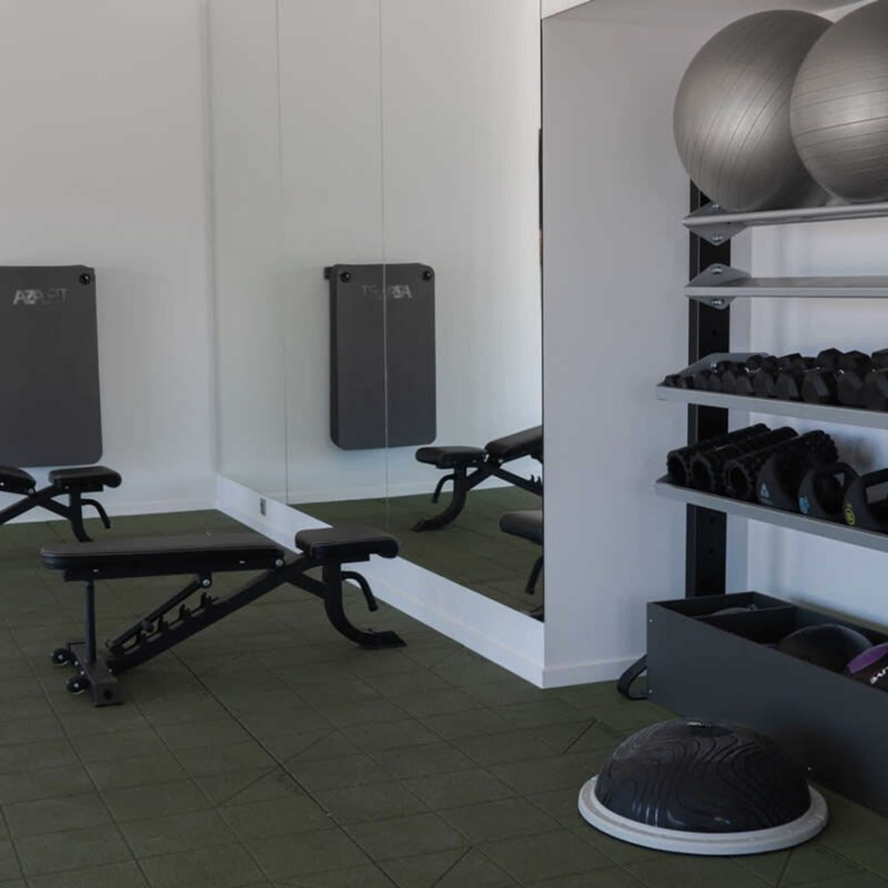 Gimnàs amb equipament esportiu, incloent bancs, peses i pilotes d'exercici.