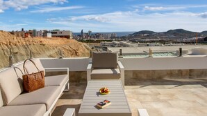 Une terrasse sur le toit avec des sièges en plein air, une vue sur le paysage urbain et une montagne lointaine.