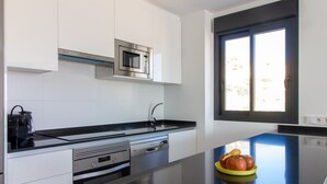 Une cuisine moderne avec des armoires blanches, un comptoir noir, un four à micro-ondes encastré et une fenêtre donnant sur l’extérieur.