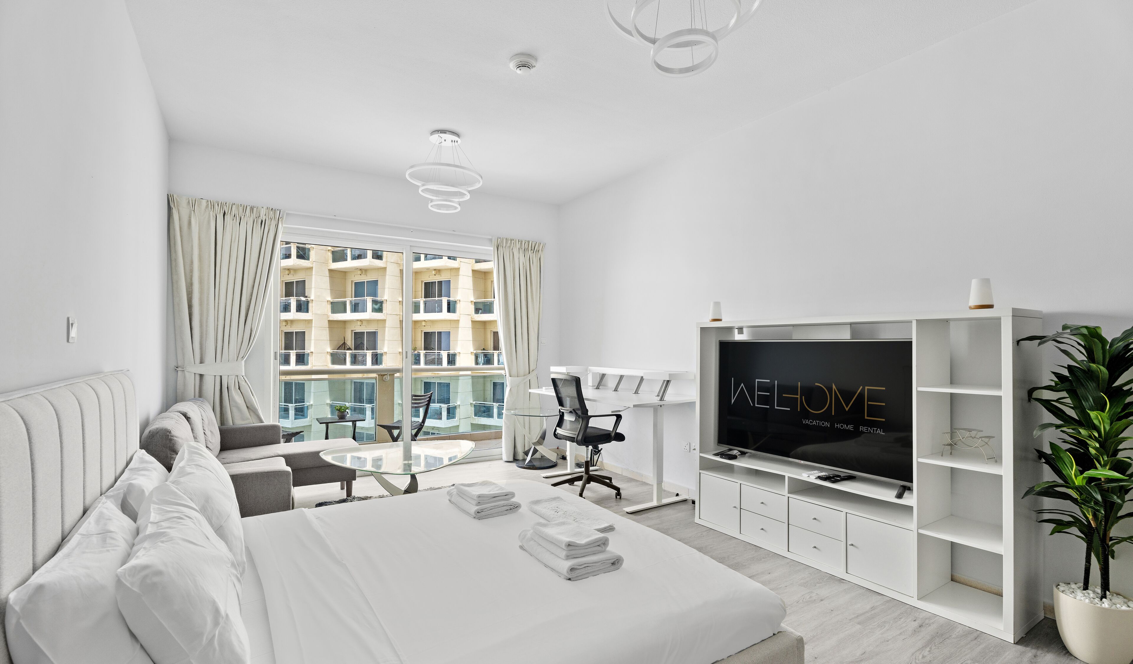 Une chambre d’hôtel moderne dotée d’un grand lit, d’une télévision, d’un bureau et d’un balcon avec des rideaux.