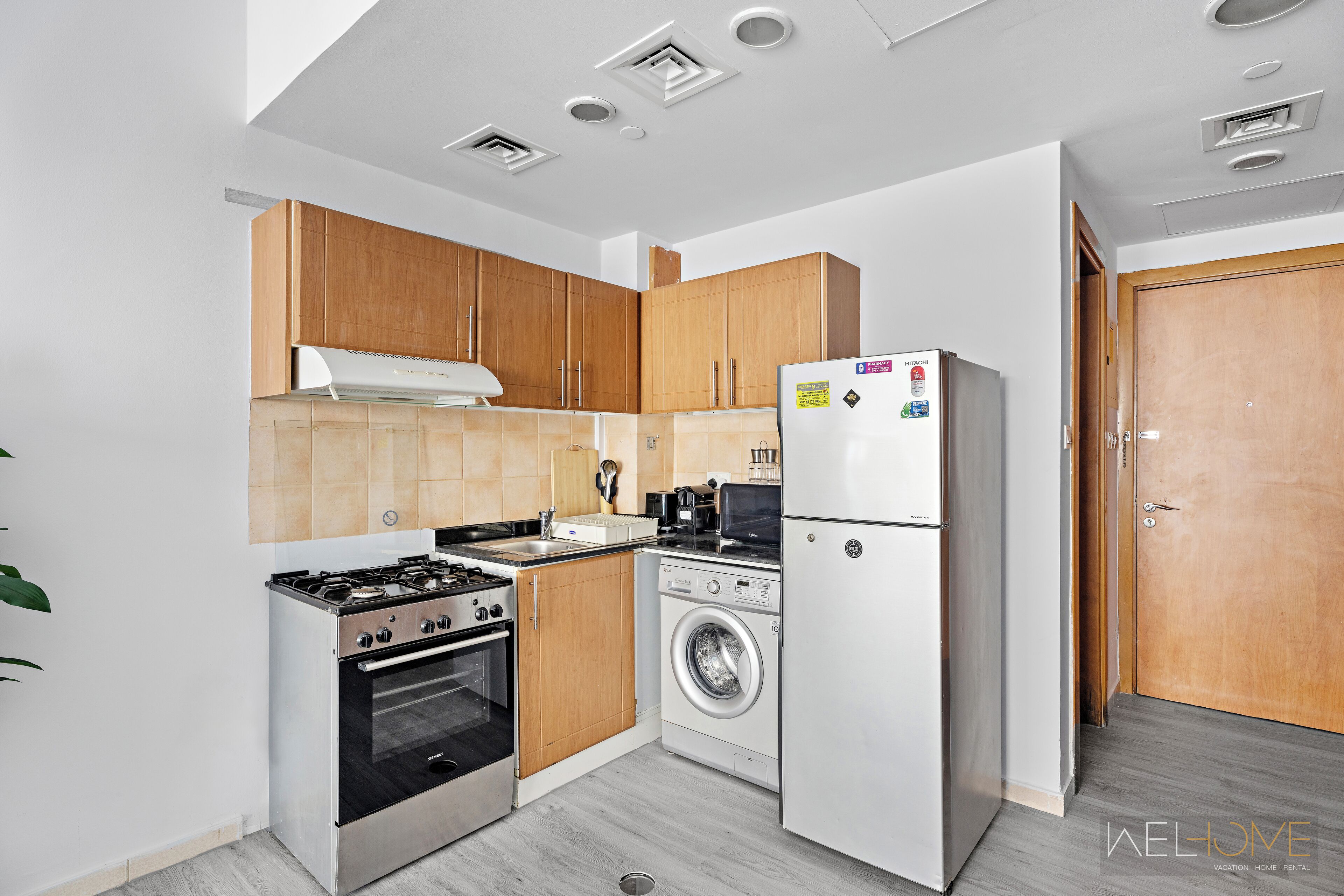 A compact kitchen with a gas stove, oven, washing machine, and refrigerator.