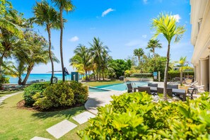 A pool area with lounge chairs and a view of the ocean.