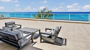 A terrace with outdoor furniture and a view of the ocean. - Luxury Penthouse Condo With 360 Oceanviews (Seven Mile Beach)