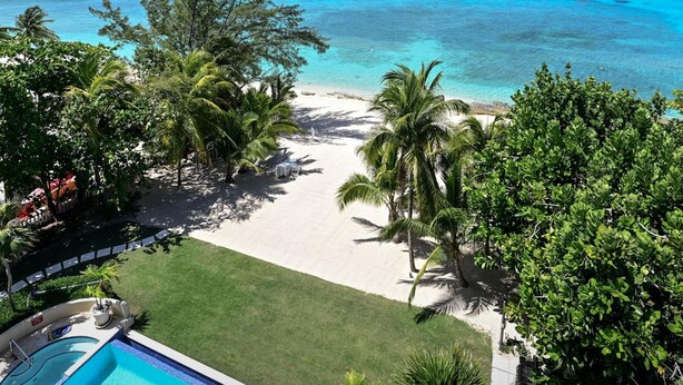 A beachfront property with a pool, palm trees, and a clear view of the ocean. - Luxury Penthouse Condo With 360 Oceanviews (Seven Mile Beach)