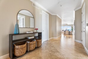 A hallway with a console table, wicker baskets, a mirror, and a view into a dining area.