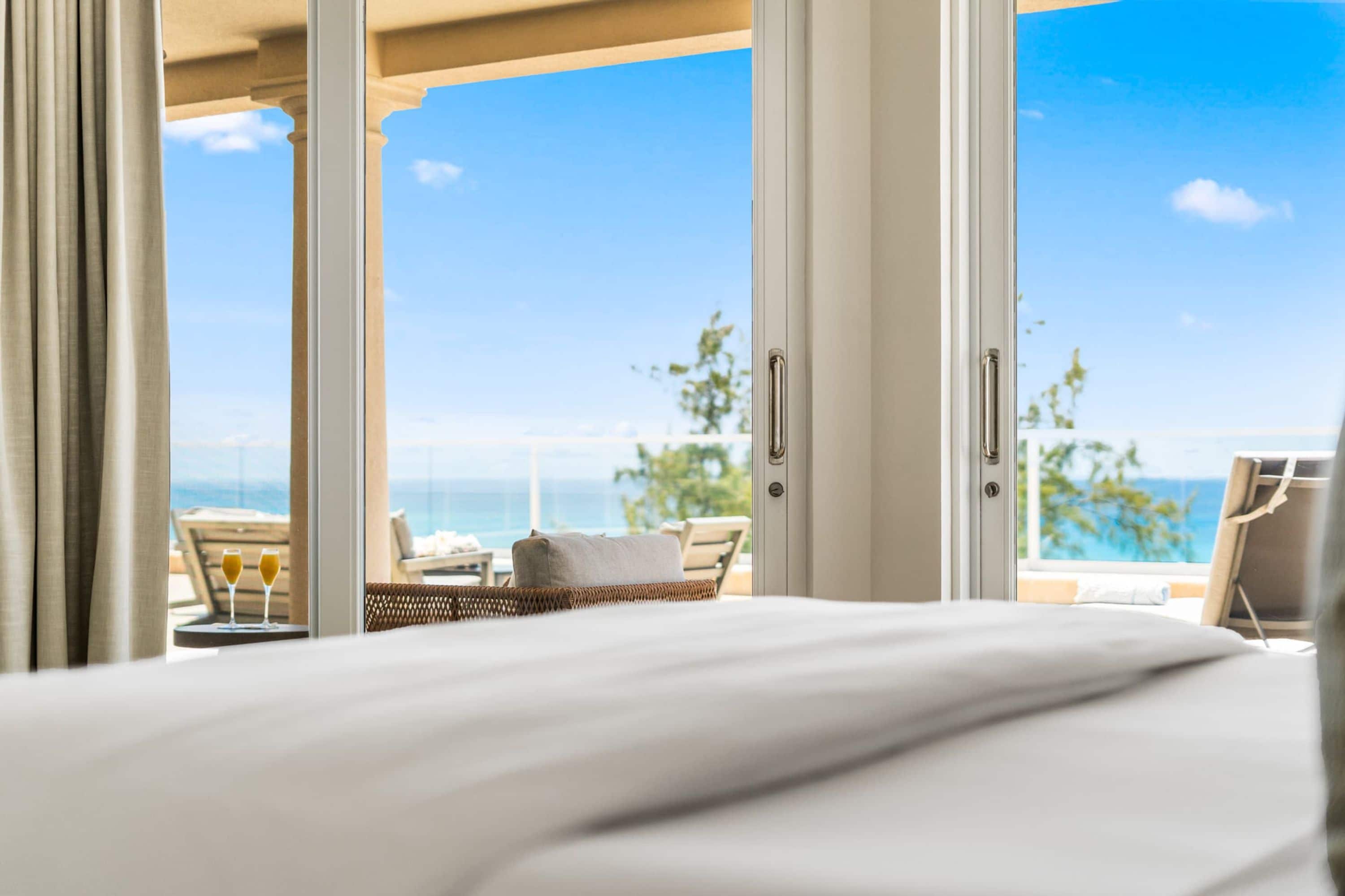 Une chambre d’hôtel avec un lit, une vue sur l’océan et un coin salon comprenant une table et des chaises.