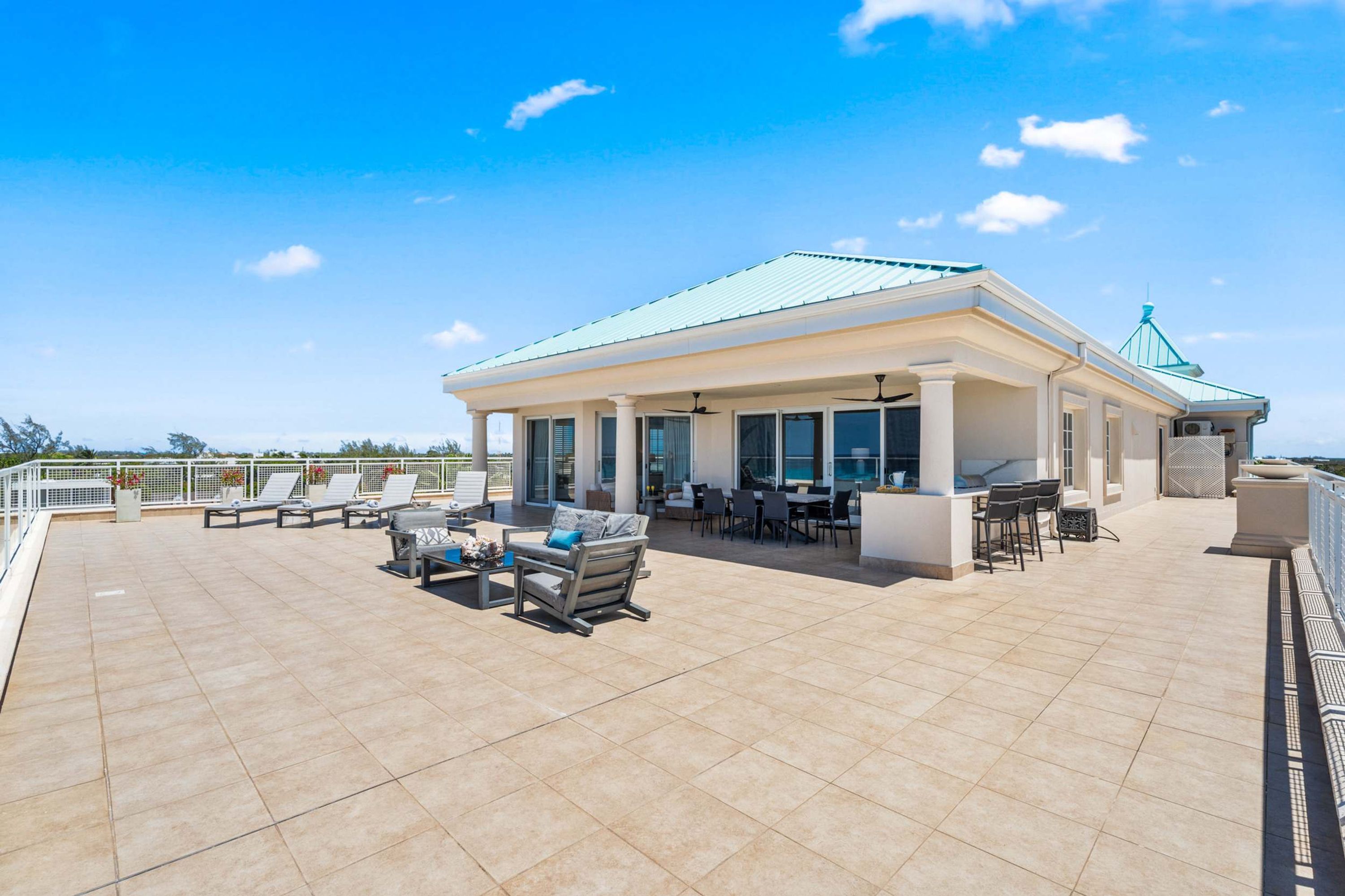 A rooftop terrace with outdoor seating, a covered area with tables and chairs, and a clear sky.