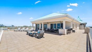 A rooftop terrace with outdoor seating, a covered area with tables and chairs, and a clear sky.